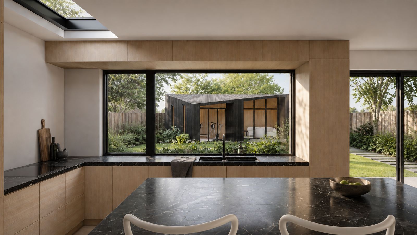 The kitchen, with a stone island and a long window framing the garden pod