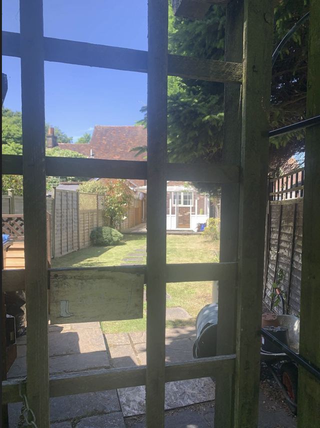 The rear of the property seen from the back gate, looking across the lawn to the conservatory and the paved side passage