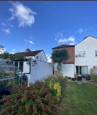 The rear of the house before the work, seen along the garden past a greenhouse