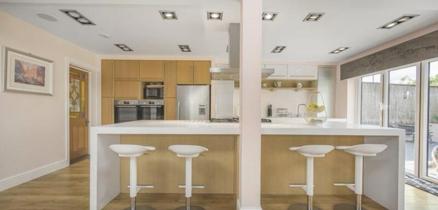 The kitchen as the house was marketed, with pale oak doors, a white island and a grid of downlights