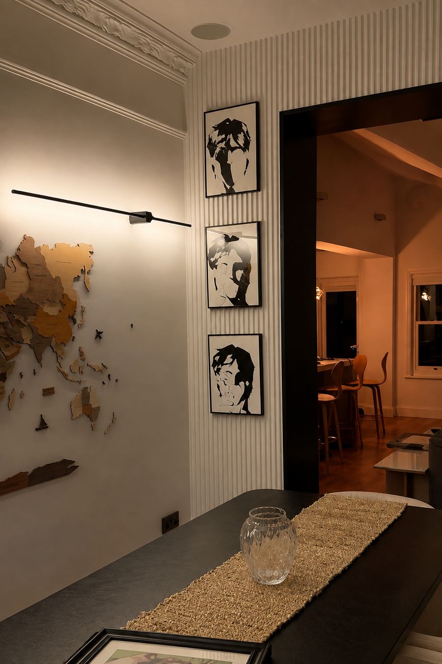 The completed dining area at night, looking through a dark-lined opening to the kitchen beyond