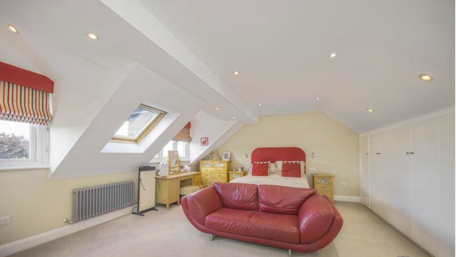 The attic bedroom as the house was marketed, with a red leather sofa, pine furniture and a dormer window