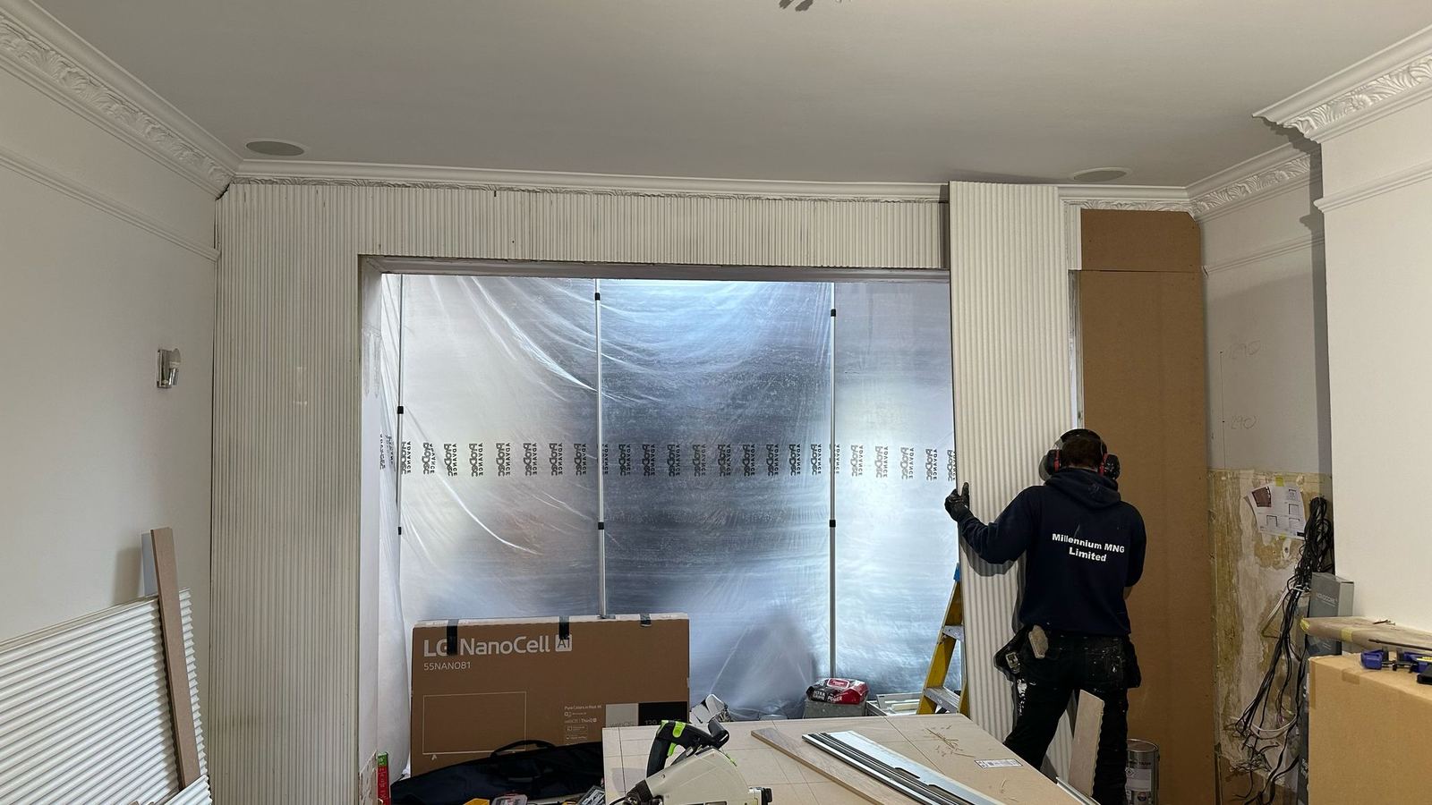 Fluted panelling being fitted around a sheeted opening, with the room protected and the cornice masked